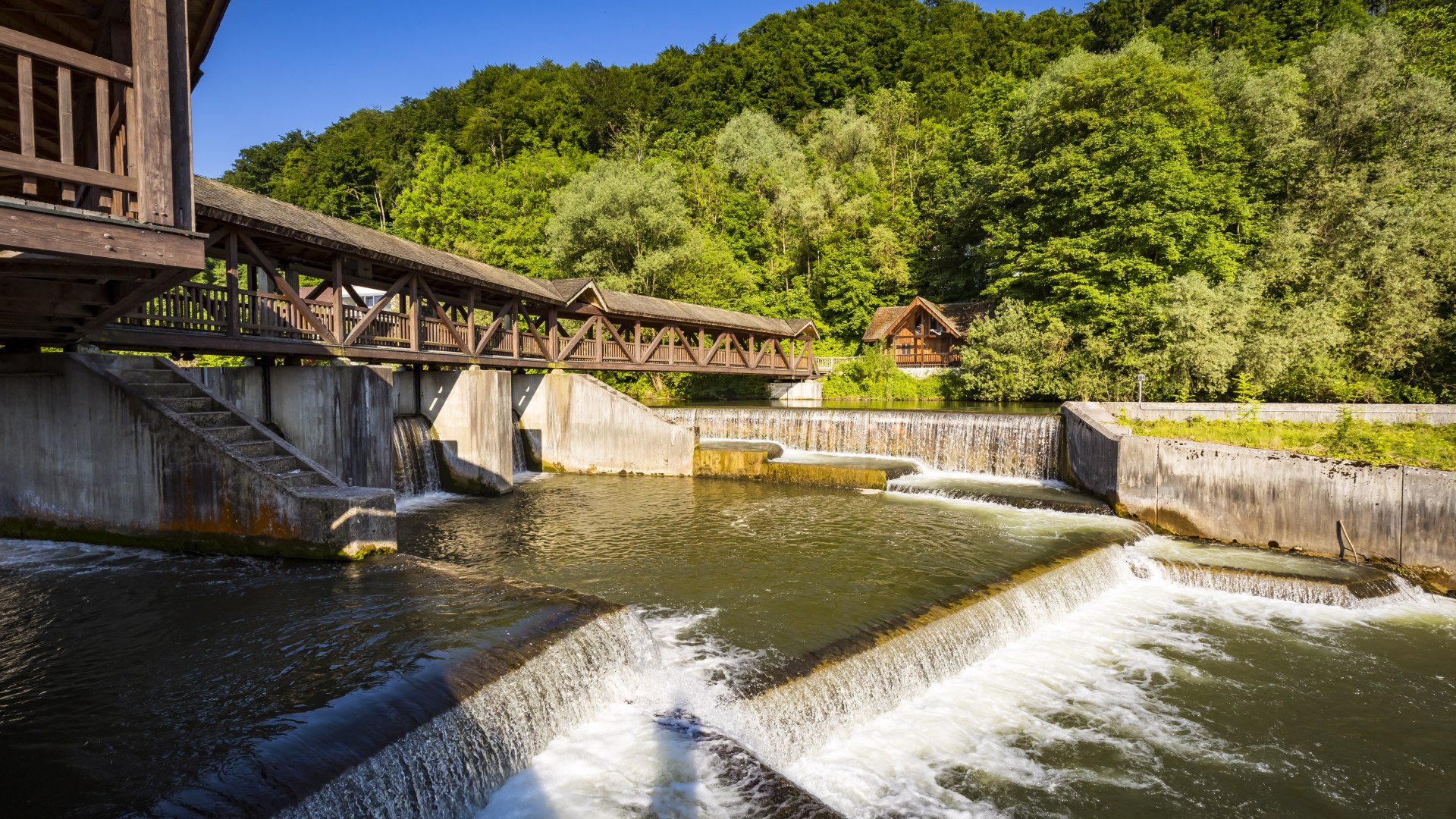 Das Kastenmühlwehr mit dem Holzgang, der überdacht ist und an die mittelalterliche Burg erinnert. Darunter die Fischtreppe, die in der Loisach angelegt wurde um den Fischen den Weg zu den Laichplätzen zu ermöglichen. , © Adrian Greiter Das Kastenmühlwehr mit dem Holzgang, der überdacht ist und an die mittelalterliche Burg erinnert. Darunter die Fischtreppe, die in der Loisach angelegt wurde um den Fischen den Weg zu den Laichplätzen zu ermöglichen. , © Adrian Greiter