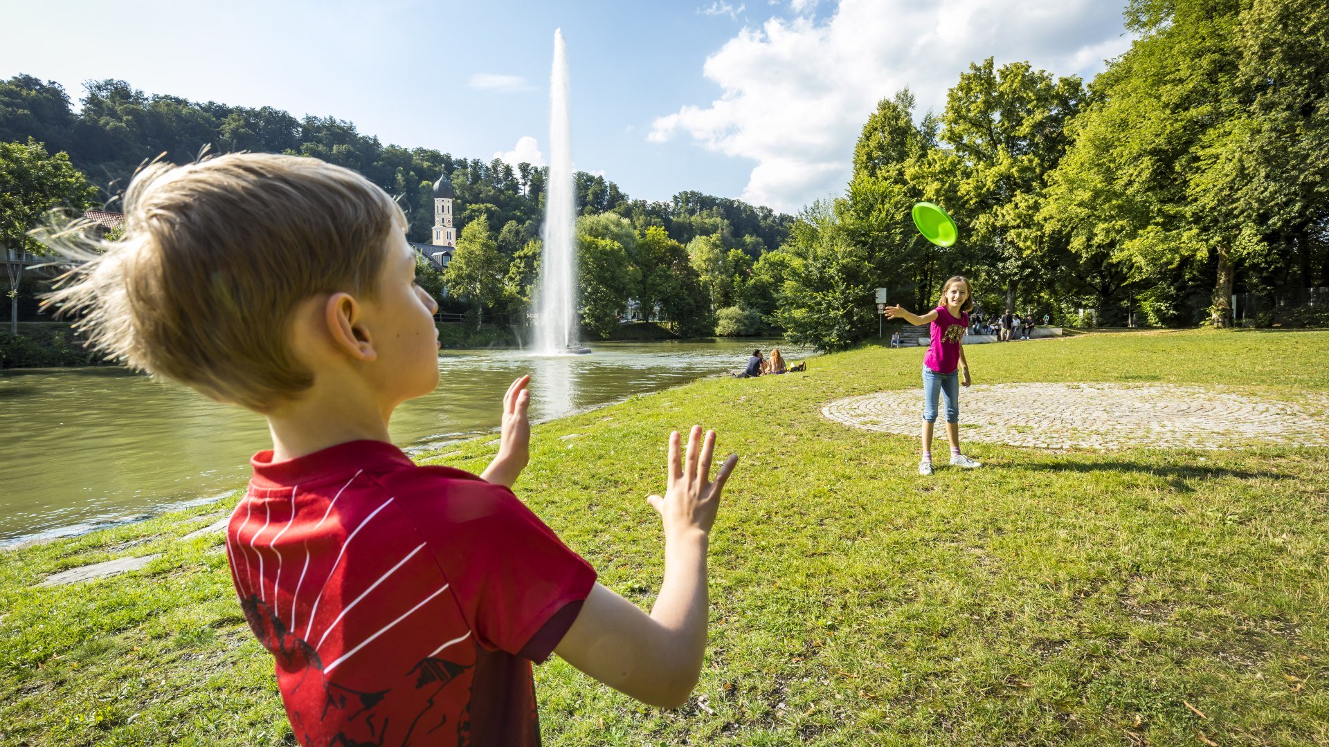 Ein Kind steht vor der einer Fontäne auf einer Wiese, © Adrian Greiter Ein Kind steht vor der einer Fontäne auf einer Wiese, © Adrian Greiter
