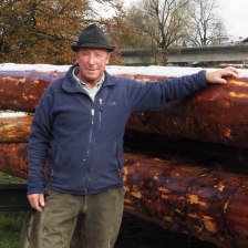 Josef Seitner mit Hut in Arbeitskleidung vor einem Stapel Baumstämme, die für ein Floß bereit liegen. Josef Seitner mit Hut in Arbeitskleidung vor einem Stapel Baumstämme, die für ein Floß bereit liegen.