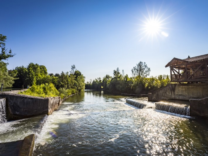 Die Loisach mit der Fischtreppe am Kastenmühlwehr gegen die Sonne fotografiert, die das Wasser glitzern lässt. , © Adrian Greiter