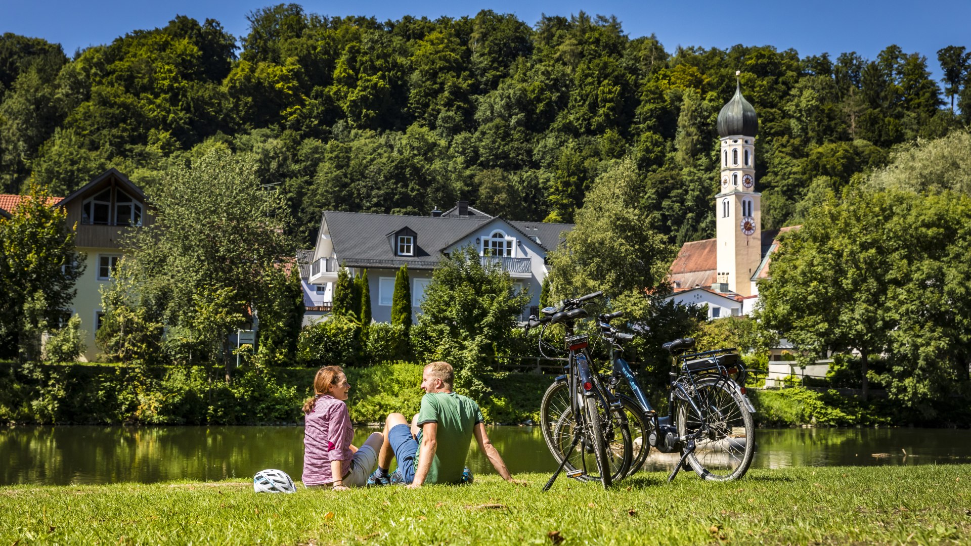 Zwei Radler machen Pause und sitzen im Gras, © Stadt Wolfratshausen Foto: Adrian Greiter