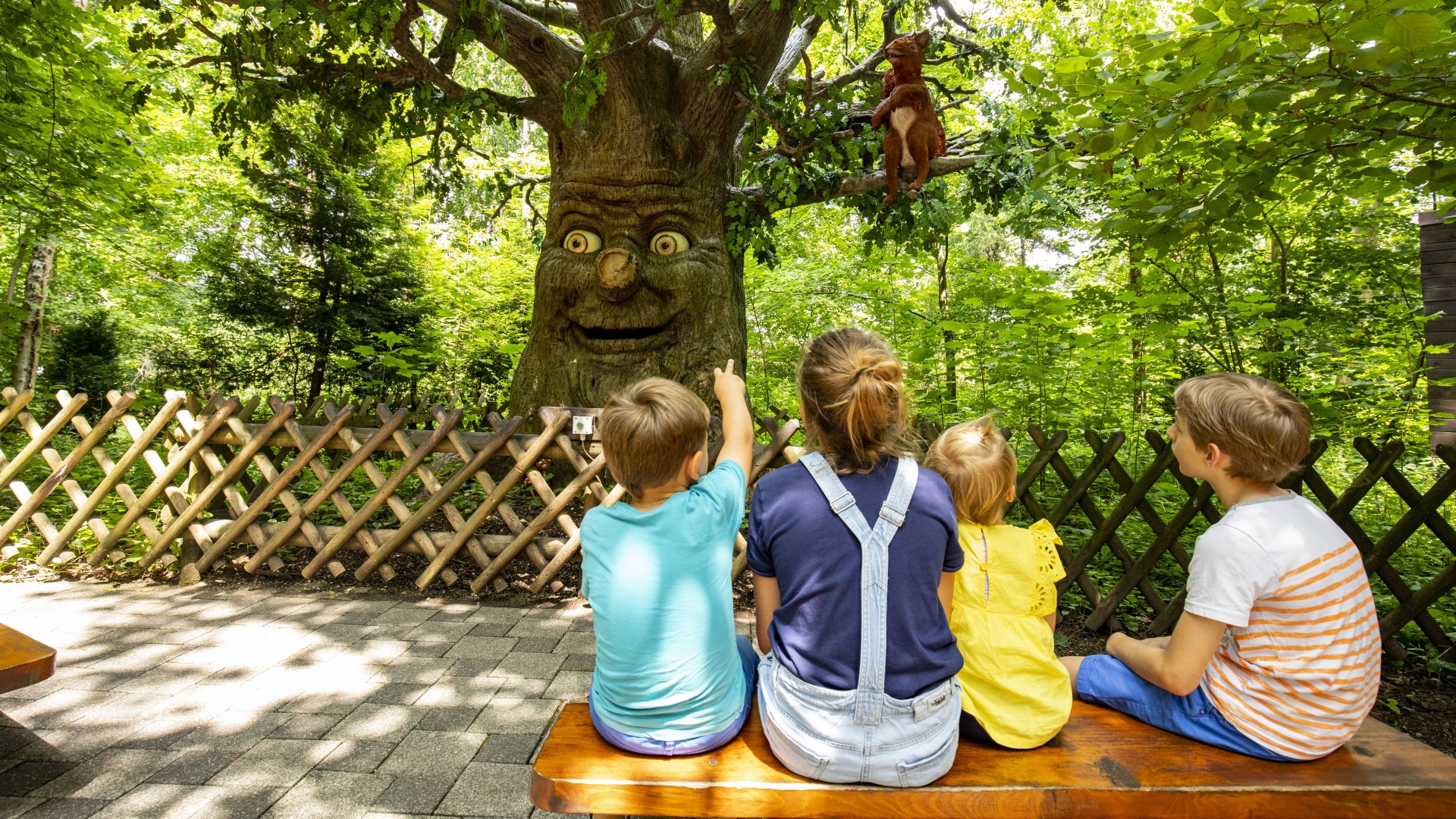 Eine Familie sitzt vor einem Märchenbaum und lauscht der Geschichte, die erzählt wird., © Stadt Wolfratshausen, Fotograf: Adrian Greiter