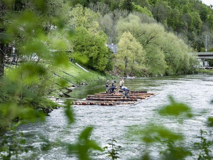 Fünf Männer arbeiten an einem Floß an der Floßlände in Weidach auf der Isar. , © Adrian Greiter