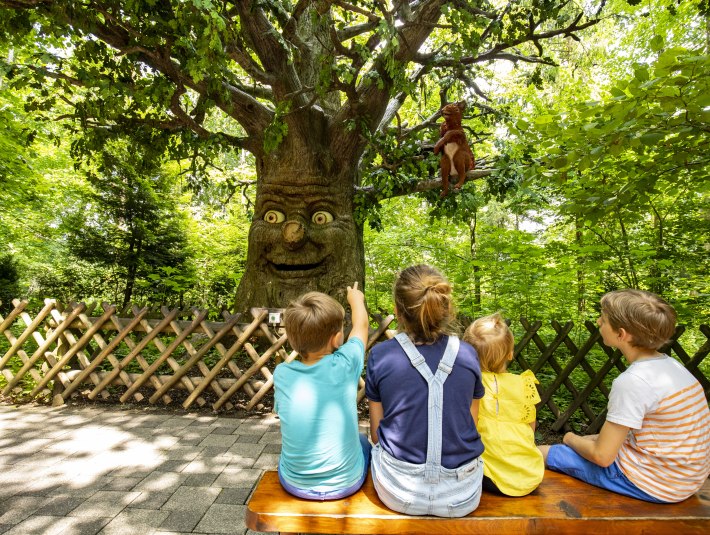 Eine Familie sitzt vor einem Märchenbaum und lauscht der Geschichte, die erzählt wird., © Stadt Wolfratshausen, Fotograf: Adrian Greiter