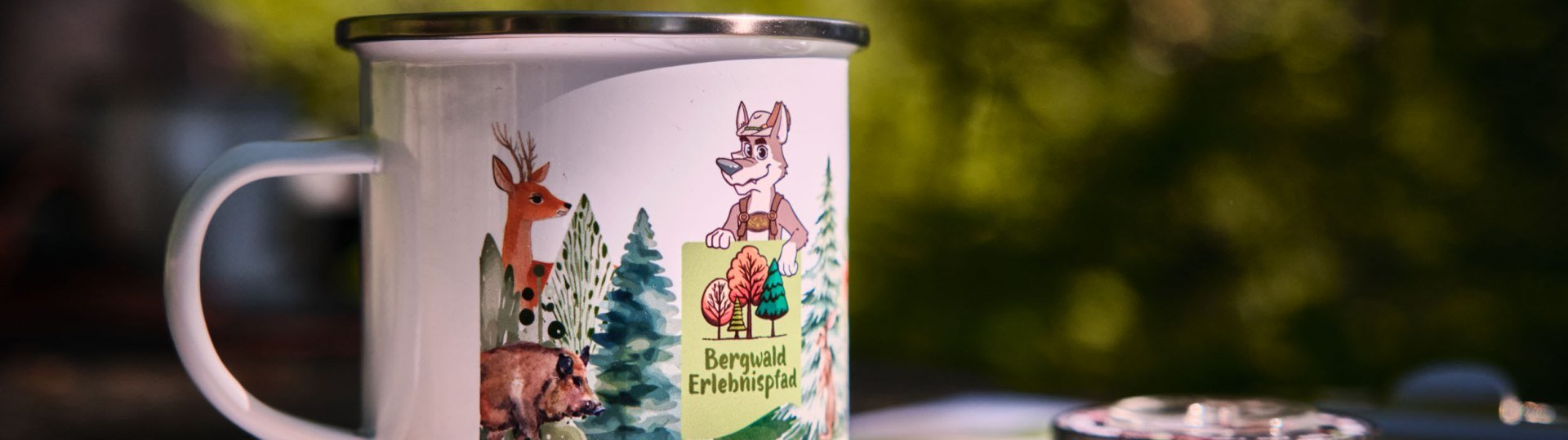 Eine Tasse mit dem Wolfi-Motiv auf dem Plan vom Bergwald-Erlebnispfad, © Stadt Wolfratshausen, Foto: Axel Pfeiler