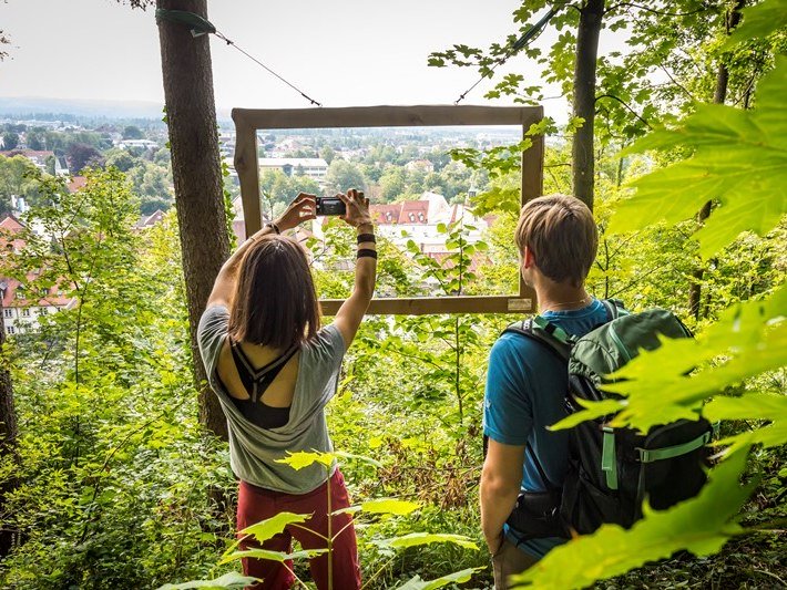 Zwei Wanderer fotografieren an einem Fotopoint die Stadt Wolfratshausen von einer Anhöhe aus. , © Adrian Greiter