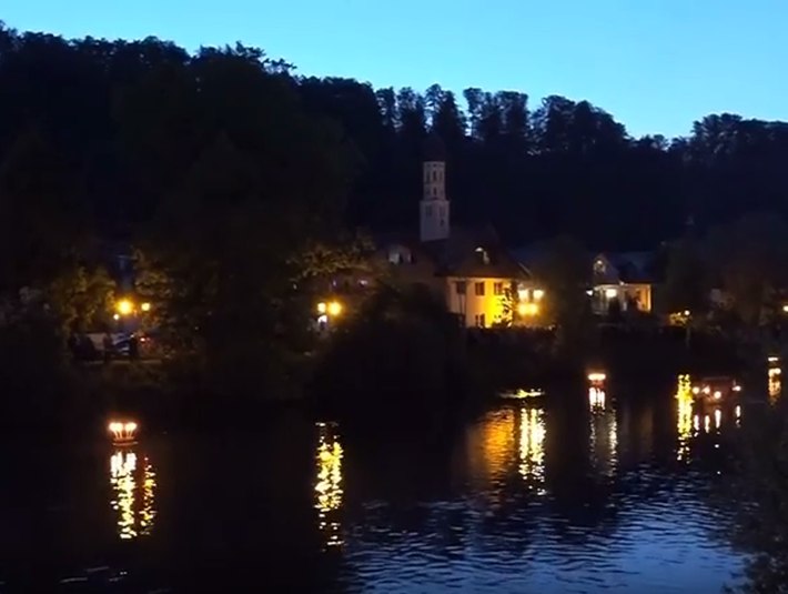 Die Loisach in der Abendd&auml;mmerung mit beleuchteten H&auml;usern am gegen&uuml;berliegenden Ufer. 