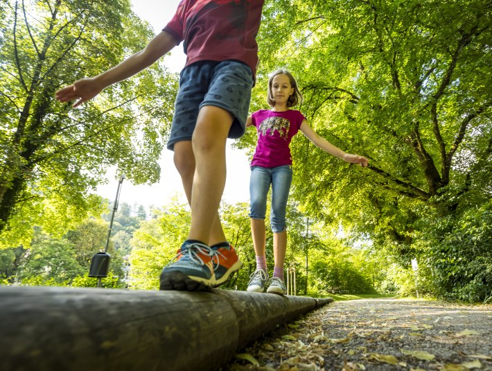 Zwei M&auml;dchen ballancieren auf einem Baumstamm, &copy; Adrian Greiter